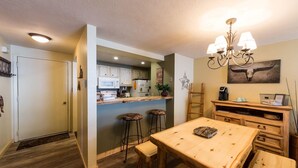 A kitchen with wooden cabinets, a bar area with stools, a dining table, and a chandelier.