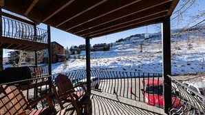 A wooden deck with chairs and a red car parked nearby.