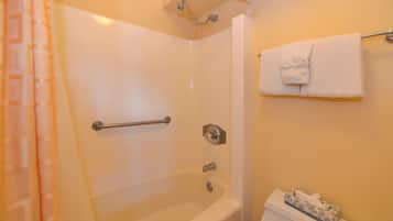 Een badkamer met een bad, een douche, een handdoekhouder en een toilet.