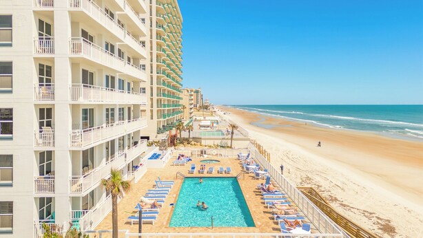 Ein Hotel mit Poolbereich, Strandzugang und mehreren Balkonen.