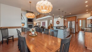 Un comedor espacioso con una mesa y sillas de madera, una cocina con electrodomésticos modernos y un dormitorio en entrepiso con balcón.