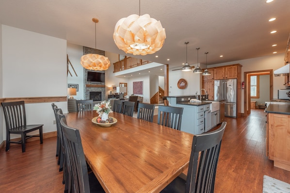 A spacious dining area with a wooden table and chairs, a kitchen with modern appliances, and a loft bedroom with a balcony.