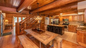 Una cocina amplia con armarios de madera, una isla central y una escalera que sube a otro nivel.