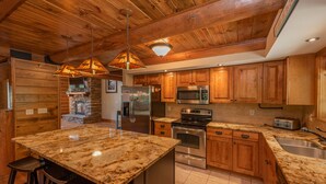 Una cocina con armarios de madera, encimeras de granito, electrodomésticos de acero inoxidable y chimenea de piedra.