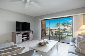 Relax in this stylish living room with a flat-screen TV, comfortable sofa, and armchair, leading to a patio with a view.