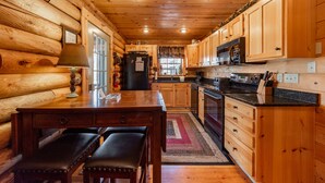 L’intérieur d’une cabane en rondins, avec une table à manger en bois, des bancs, un réfrigérateur, un four à micro-ondes et des armoires en bois.