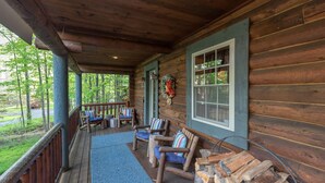 Une cabane en bois avec une véranda, deux fauteuils à bascule et une cheminée.