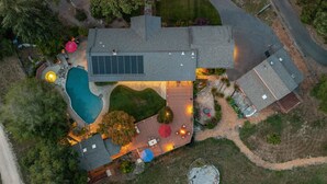 An aerial view of a residential property with a swimming pool, patio, and a detached garage.