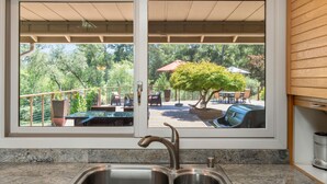A kitchen with a double sink and a view of an outdoor patio with a barbecue grill and seating area.