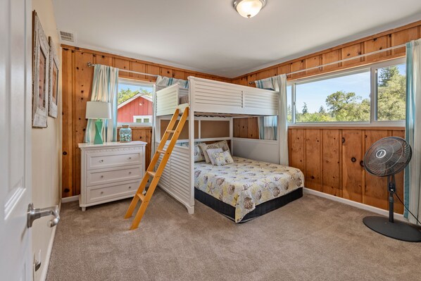 A bunk bed room with a wooden floor, a white dresser, a ladder, a fan, and a window with curtains. - Fallen Tree Ranch ~ 3 Acres in Wine Country, Pool, Hot Tub, Sauna (Sebastopol)