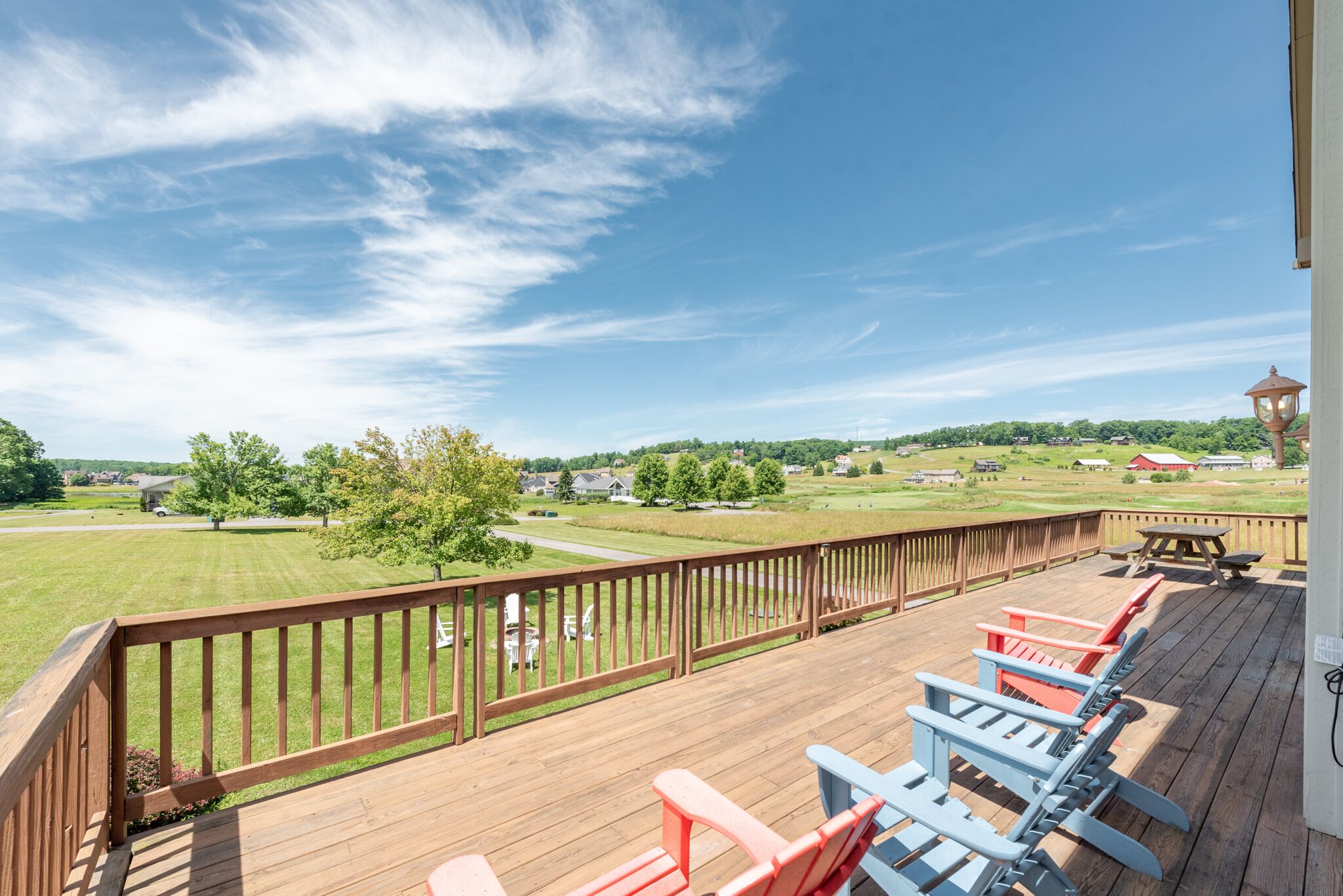 Eine Holzterrasse mit Sitzgelegenheit und Blick auf eine grüne Landschaft.