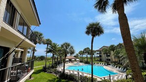 Une piscine entourée de palmiers et un bâtiment doté de balcons.