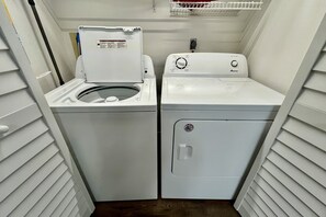 Une petite buanderie équipée de deux machines à laver à chargement frontal blanches et d’un sèche-linge.