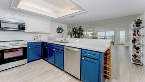 Cocina moderna con armarios blancos, detalles en azul y una isla central.