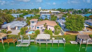 A resort with a swimming pool, thatched-roof structures, and a dock. - P34 - Beautiful 4 bedroom 2 bath, single family home with private pool and deep water dockage. (Key Colony Beach)