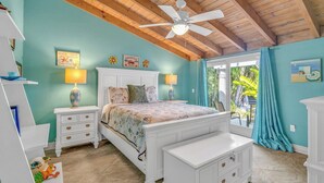 A bedroom with a bed, nightstands, a dresser, a ceiling fan, and a view of the outdoors. - P34 - Beautiful 4 bedroom 2 bath, single family home with private pool and deep water dockage. (Key Colony Beach)