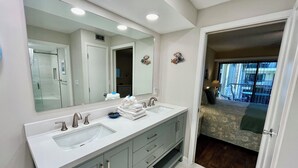 A modern bathroom with dual sinks, a large mirror, and a walk-in closet. - Soak up the Florida sunshine in this spacious poolside condo with views of the ocean. (Saint Augustine)