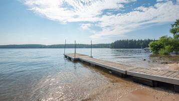 Guests can enjoy serene lakeside views from the dock with railings, surrounded by lush greenery and a distant island.