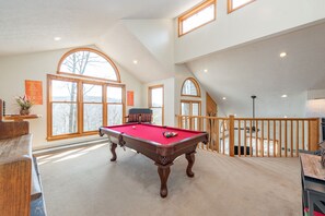 A spacious room with a pool table, large windows, and a view of the outdoors.