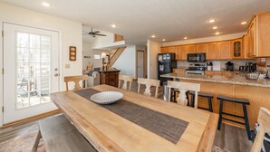Una cocina amplia con armarios de madera, una isla central y un comedor con una mesa grande y bancos.