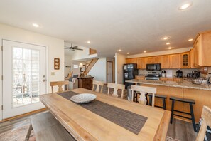 A spacious kitchen with wooden cabinets, a central island, and a dining area with a large table and benches.