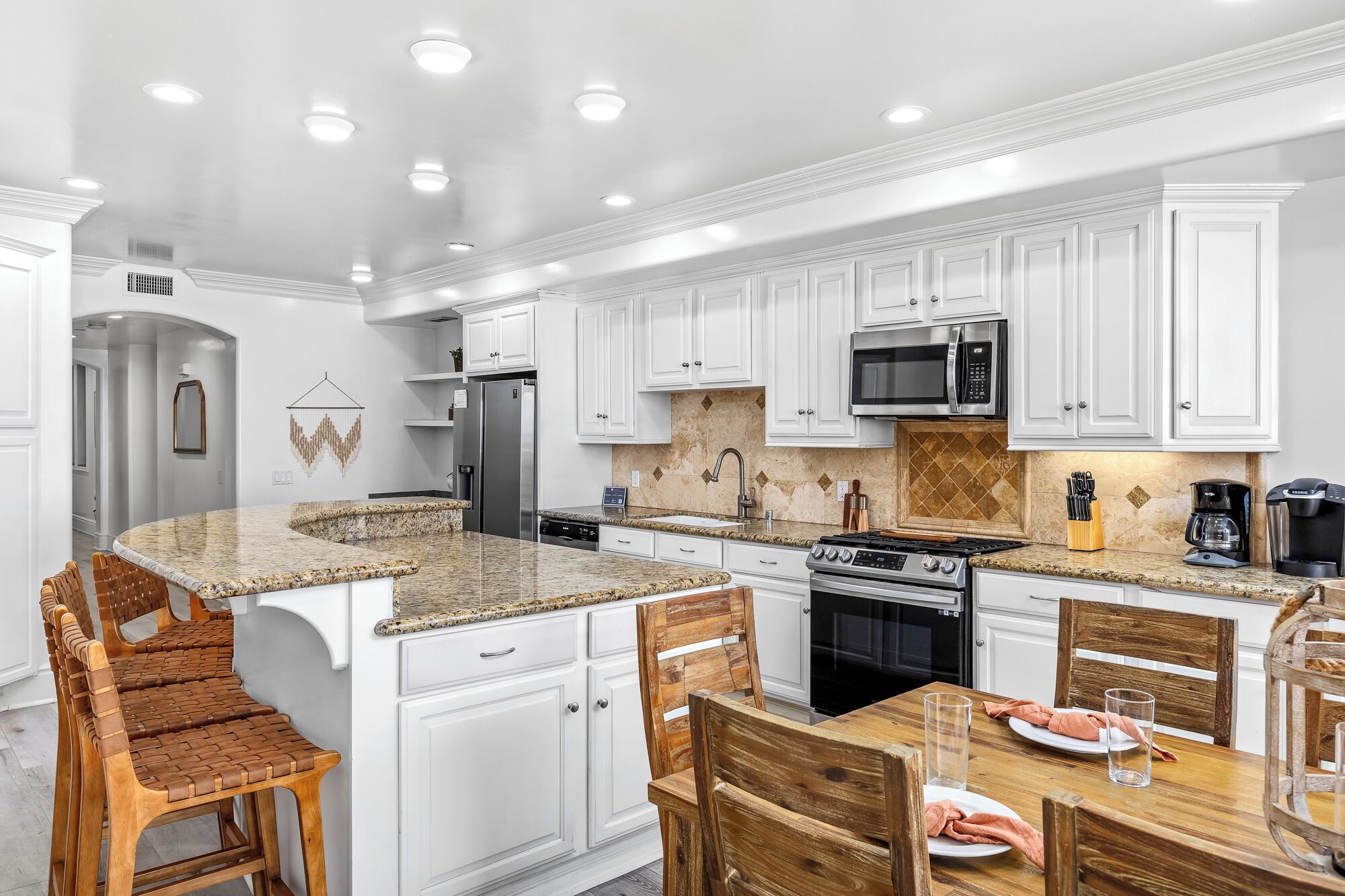 A modern kitchen with white cabinetry, granite countertops, and stainless steel appliances.
