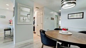 A dining area with a round wooden table, black chairs, and a decorative centerpiece. - Pelican Cove 12 -  Anna Maria Island - Across the street from the beach- Condo  2 Bedroom /2 Bath bay view with a community pool,  maximum occupancy of 6 people. (Bradenton Beach)
