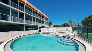 Ein Swimmingpool mit Liegestühlen und ein Gebäude mit Balkonen.