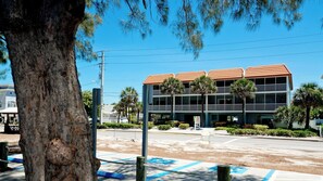A two-story building with a red-tiled roof, surrounded by palm trees and a clear blue sky.