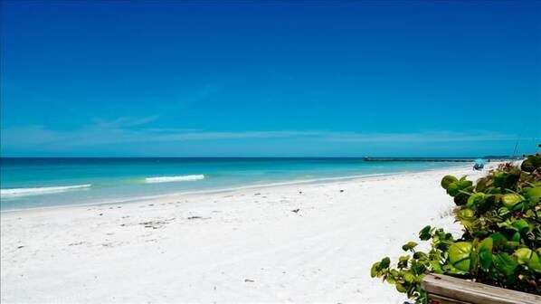 A beach with white sand and clear blue water.