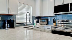 A modern kitchen with a built-in coffee maker, a toaster, and a microwave.