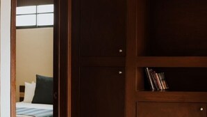 Une chambre à coucher avec un lit, une armoire et une petite étagère remplie de livres.