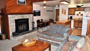 Una sala acogedora con chimenea, un sofá, una mesa de comedor y una zona de cocina.
