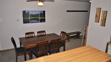 A dining area with a wooden table and chairs, a ceiling fan, and a wall-mounted picture.