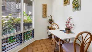 A dining area with a white table, wooden chairs, and a potted plant. - Watch Waves from Lanai w/Wet Bar! Full Kitchen, WiFi, TV, Washer/Dryer Kanaloa 2902 (KAILUA-KONA)