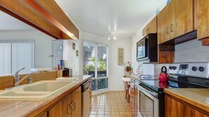 A kitchen with wooden cabinets, a double sink, a stove, and a microwave. - Watch Waves from Lanai w/Wet Bar! Full Kitchen, WiFi, TV, Washer/Dryer Kanaloa 2902 (KAILUA-KONA)