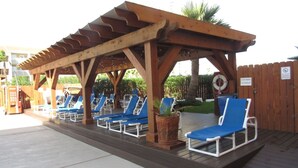 Una pérgola de madera con sillones azules y una terraza de madera.
