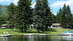 A lakeside property with docked boats, a grassy area, and a large tree. - Swim, Ski & Scenic Lake Views by Deep Creek Lake (MCHENRY)