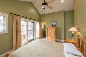 A bedroom with a large bed, a ceiling fan, a wooden cabinet, and a nightstand with a lamp. - Swim, Ski & Scenic Lake Views by Deep Creek Lake (MCHENRY)