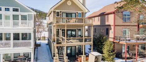 A multi-story house with a balcony, a staircase, and a covered outdoor area.