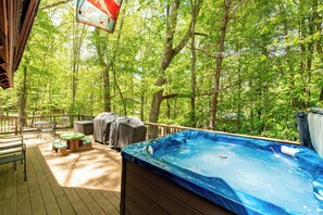 Een hottub op een houten terras, omringd door een bos.