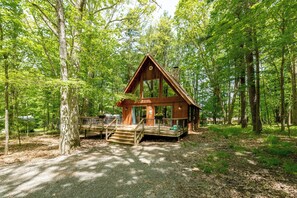 Een chalet met een houten terras, een veranda en een stenen schoorsteen.
