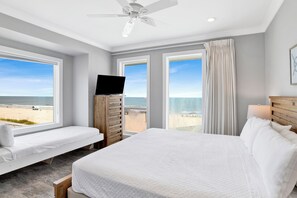 Une chambre avec un grand lit, une télévision et une vue sur la plage.