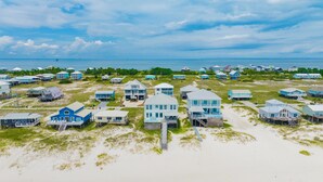 A coastal area with multiple beachfront houses, some with decks and others with direct beach access.