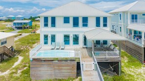Une maison située en bord de mer, dotée d’une piscine, de plusieurs terrasses et offrant une vue sur l’océan.