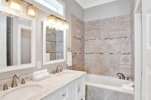 Une salle de bain avec deux lavabos, un grand miroir et une baignoire.