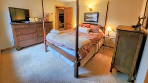 A four-poster bed with a wooden headboard, a television on a dresser, and a lamp on a nightstand. - Townhome in Crested Butte | 3 Bedroom | Walk to Elk Ave | Gas Grill | Parking (Crested Butte)