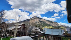 A mountain view with a clear sky, houses with metal roofs, and a wooden deck. - Townhome in Crested Butte | 3 Bedroom | Walk to Elk Ave | Gas Grill | Parking (Crested Butte)