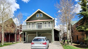 A two-story house with a garage, a balcony, and a driveway with a parked car. - Townhome in Crested Butte | 3 Bedroom | Walk to Elk Ave | Gas Grill | Parking (Crested Butte)