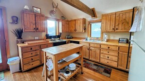 A rustic kitchen with wooden cabinets, a central island, and a mounted deer head. - Townhome in Crested Butte | 3 Bedroom | Walk to Elk Ave | Gas Grill | Parking (Crested Butte)